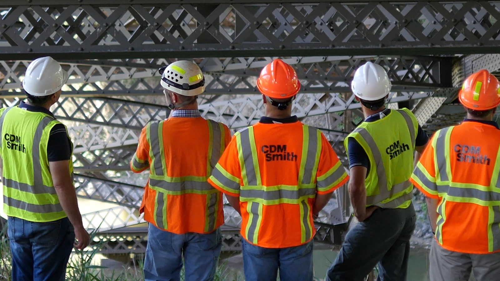 Five construction field staff, including CDM Smith employees, evaluating the underside of a bridge