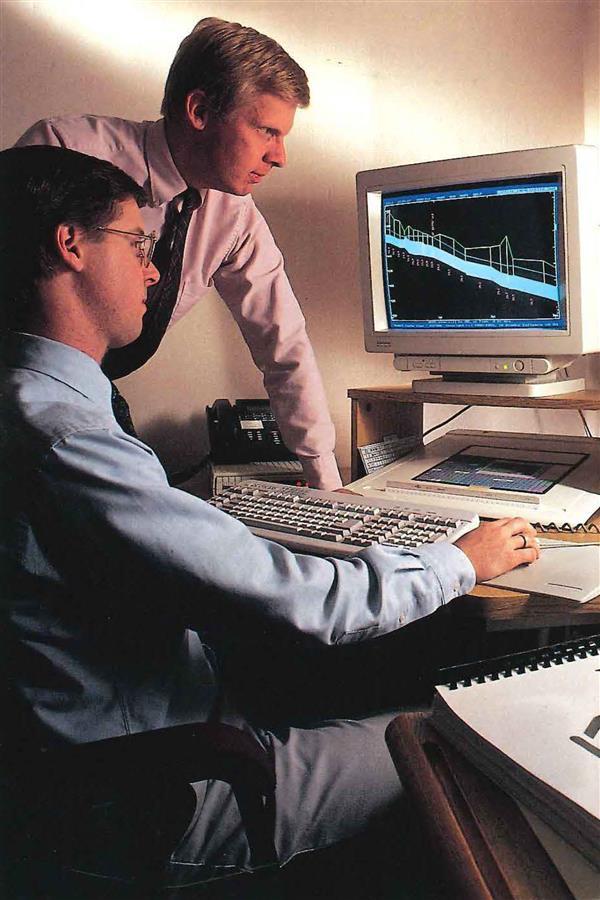 Newspaper clipping of two men looking at computer screen, 90s