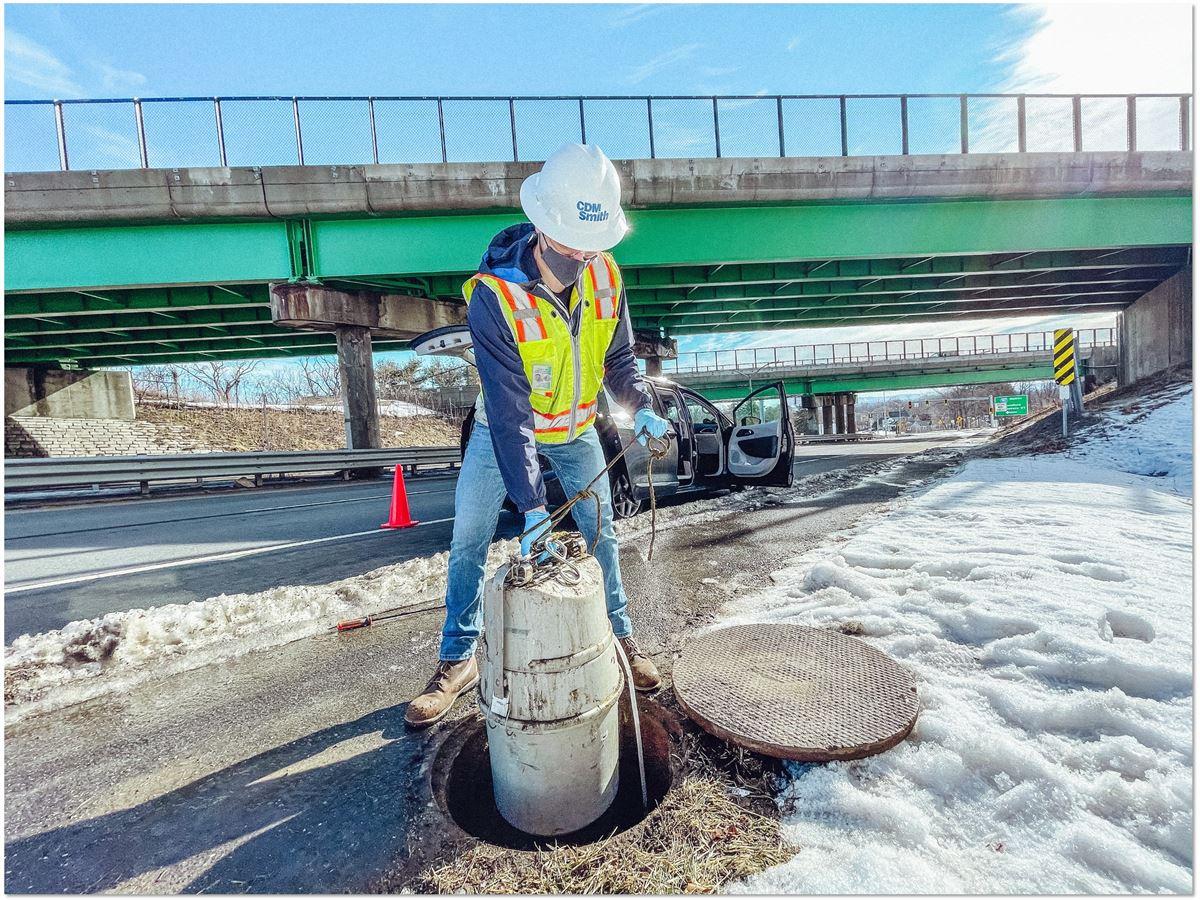 A CDM Smith employee removing wastewater from a sewage hole