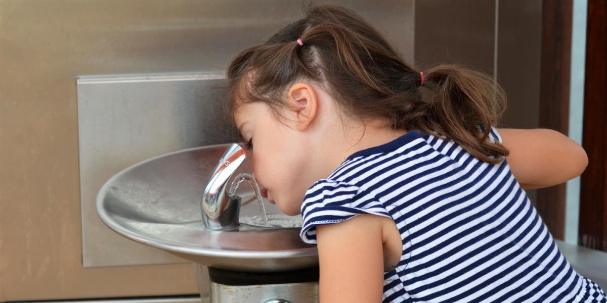 A young girl at a drinking water fountain
