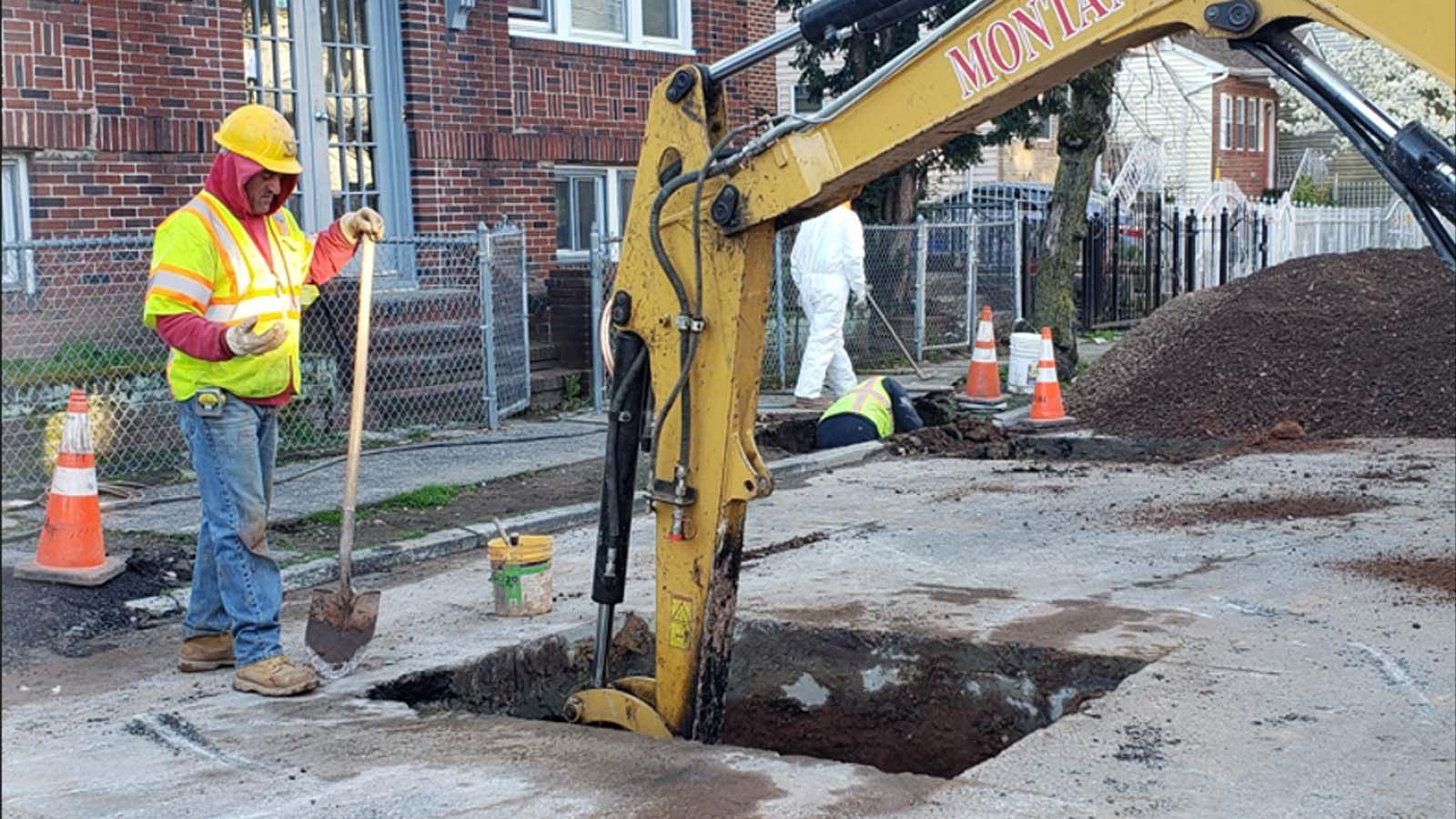 Man supervising an excavator digging in the street