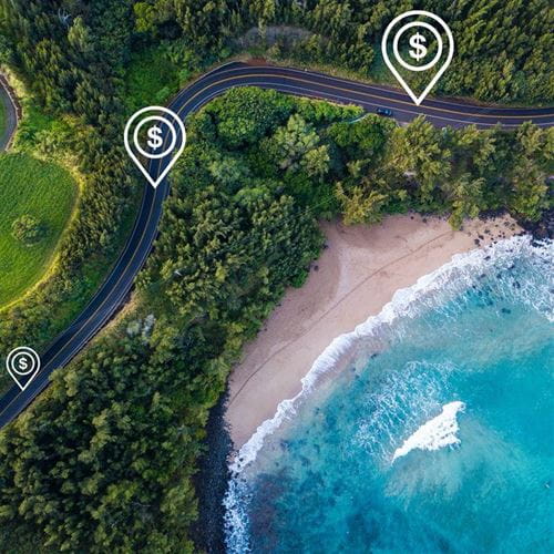 An aerial view of a highway in Hawaii, with illustrations of dollar signs conveying road usage charges.