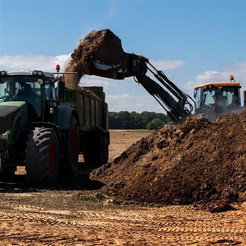 Front loader loading biosolids in dump truck