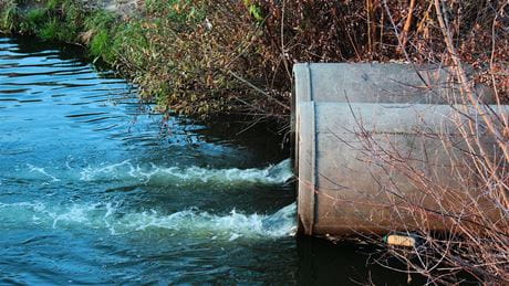 PFAS Wastewater webinar hero image, sewage draining into a river